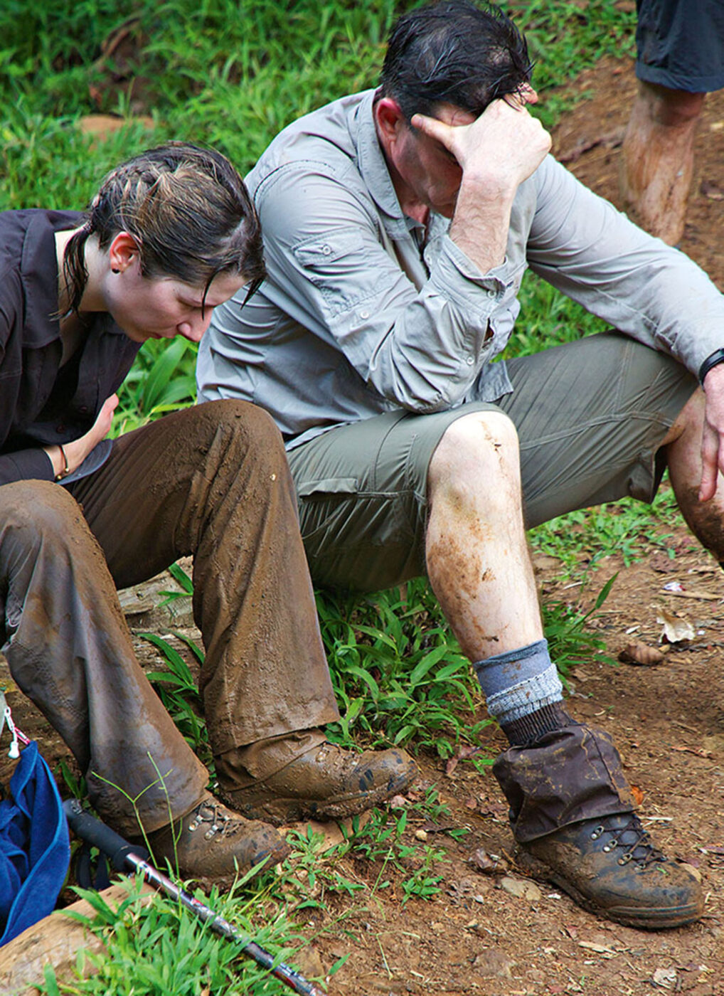 Two people sitting down, looking wet, dirty and very exhausted.