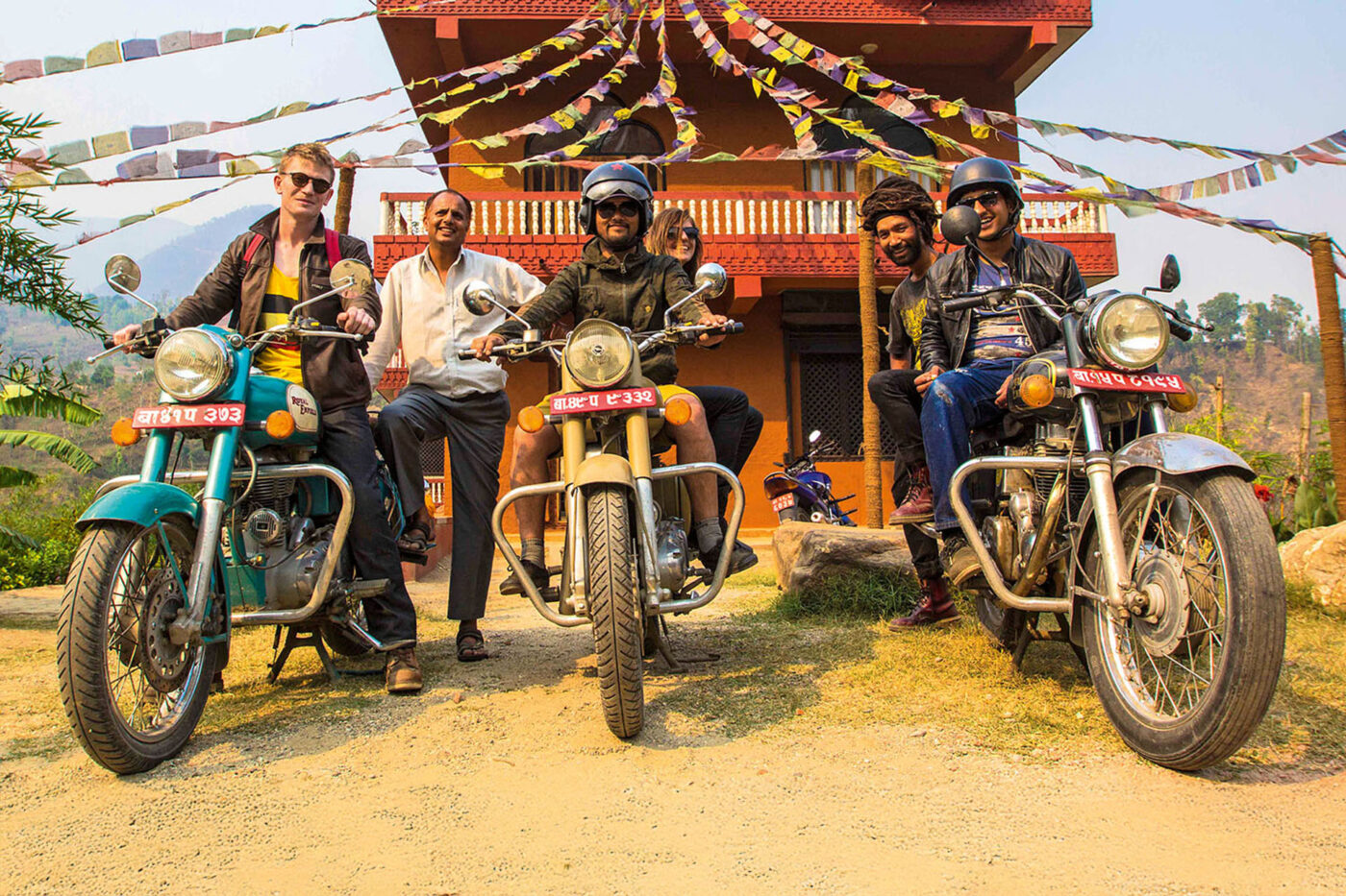 Three people on motorcycles, with three other people posing behind them.