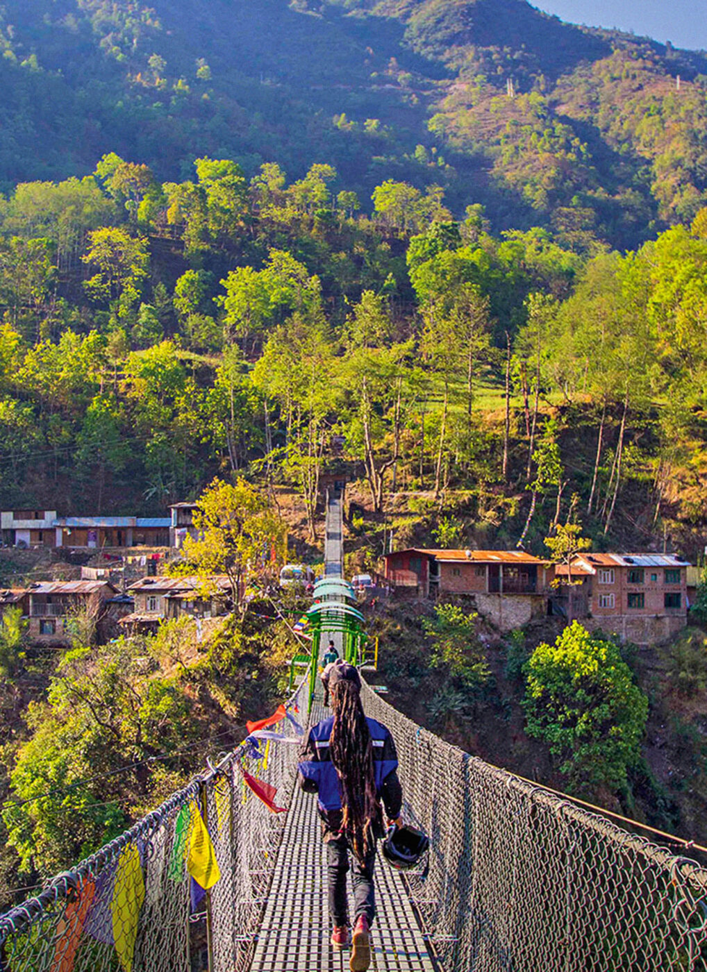 A person walking down a high-up bungee bridge that goes from the resort to the town.