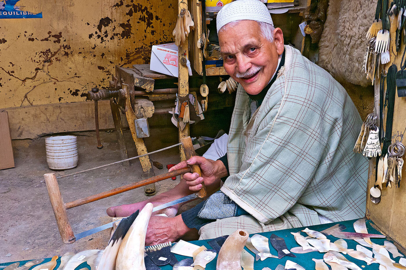 An old man sawing into bone and smiling to the camera.