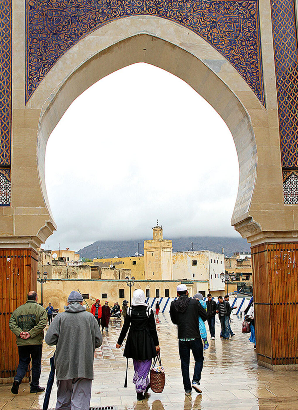 A group of people walking through a circular gate.