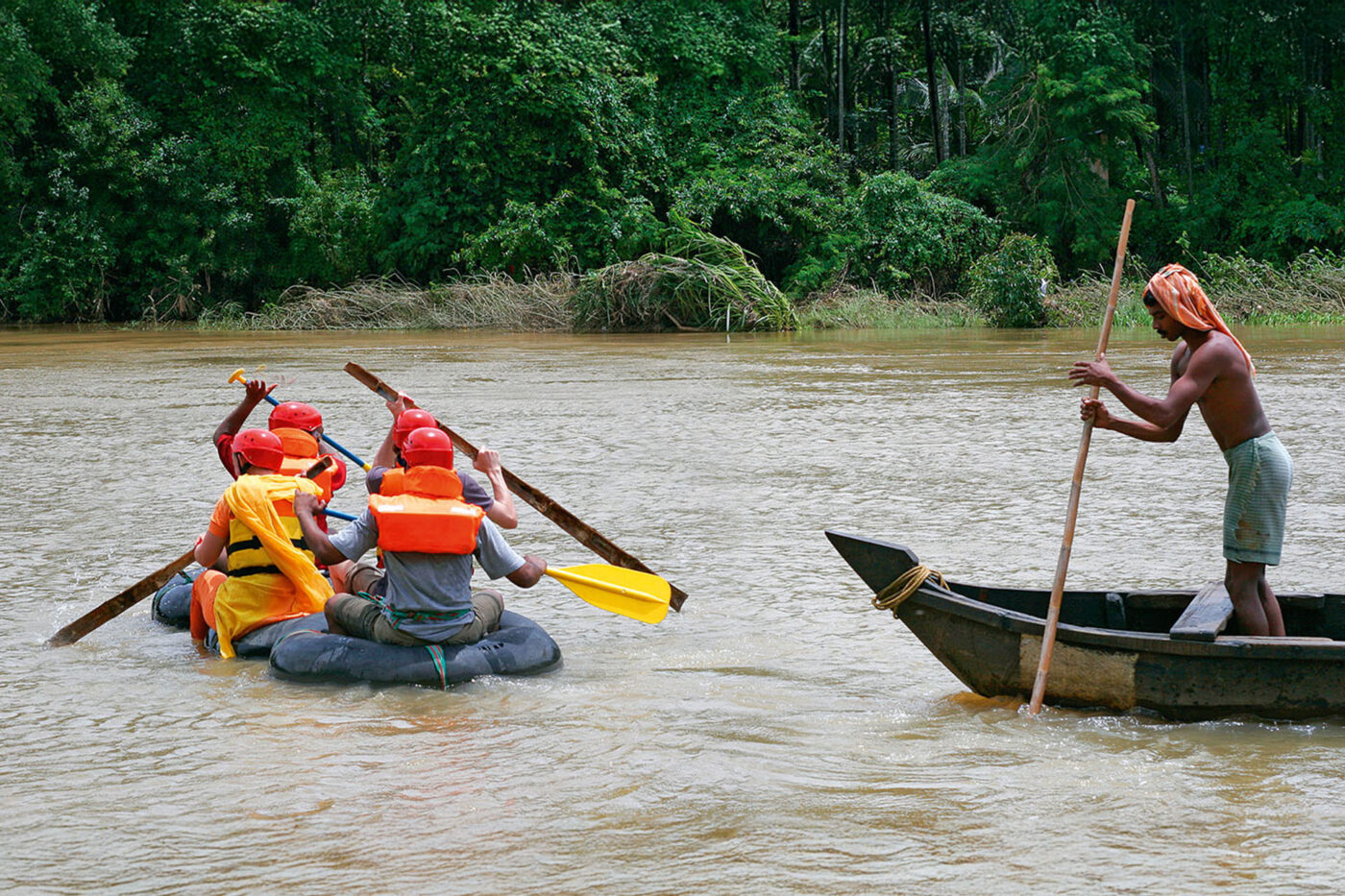 A group of people with kayaks on a floating device. A boy in a boat is stand-up rafting.
