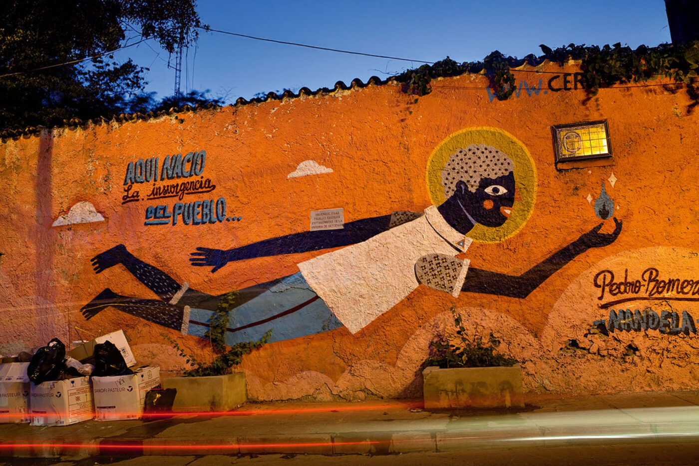 An orange murial depicting an Afro-Colombian floating in the air and holding a flame.