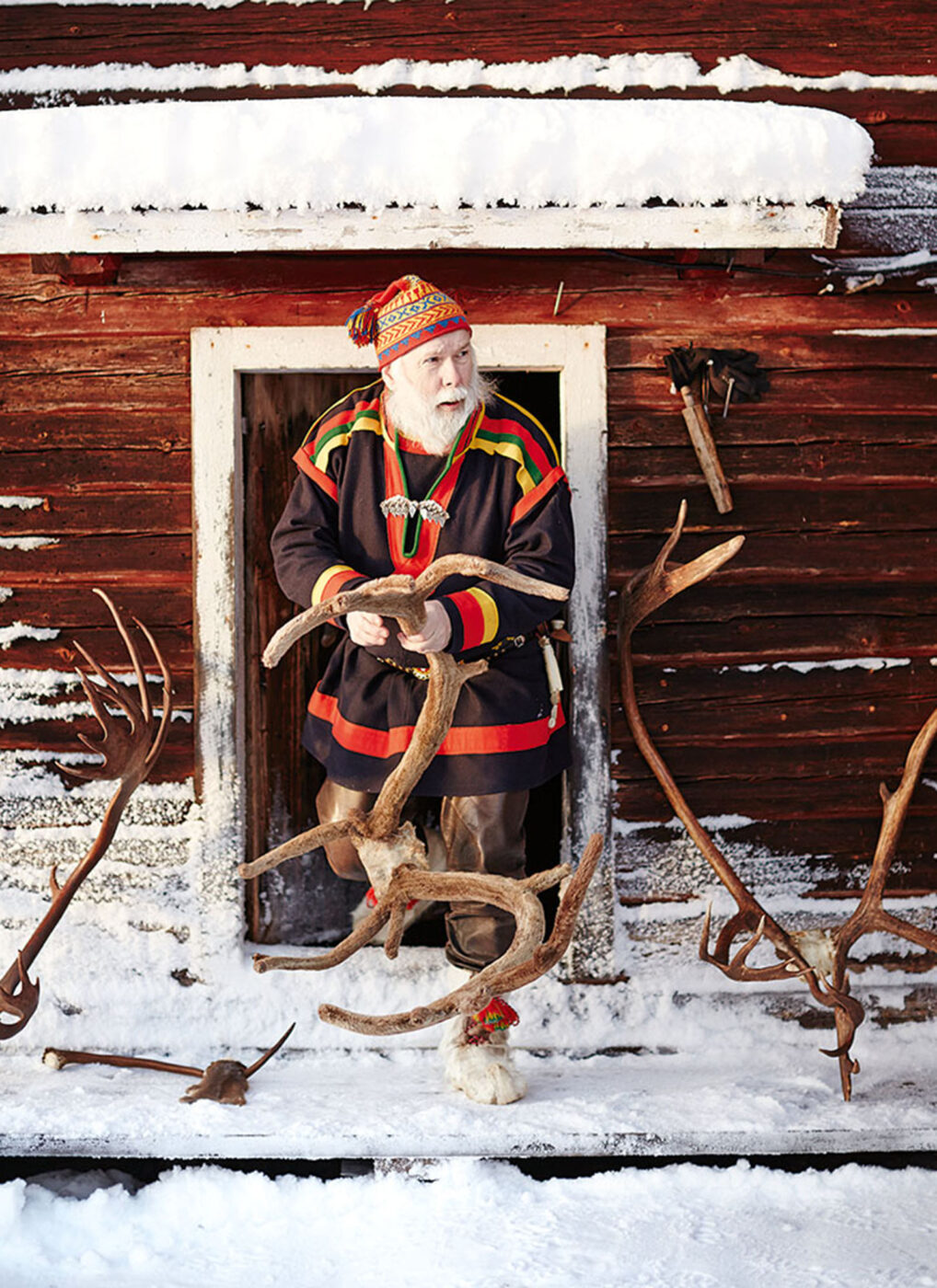 An older man with a white beard holding reindeer antlers.