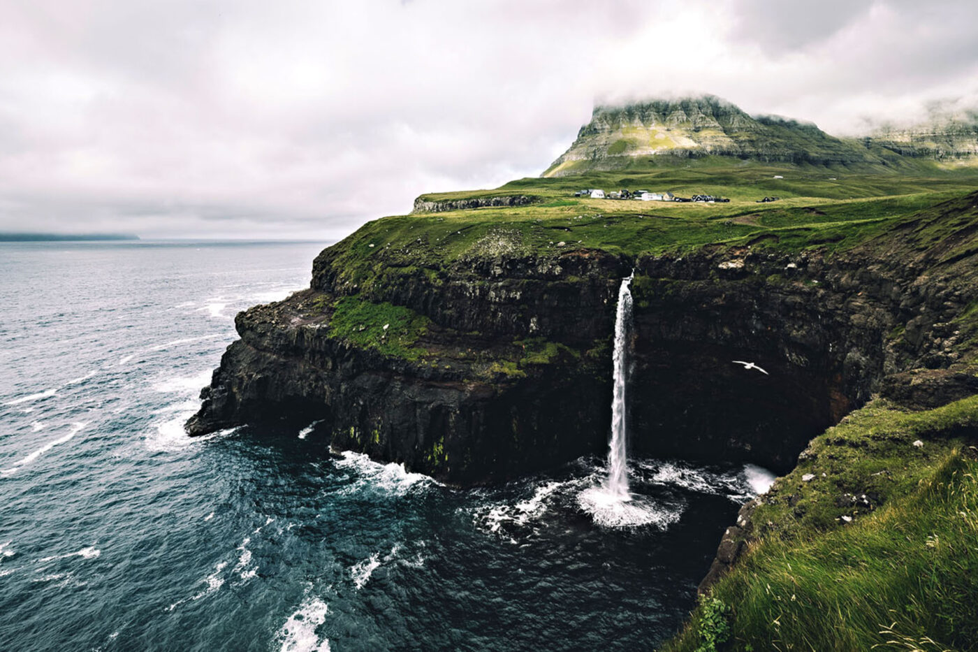 A cliff with a large waterfall that's falling into the sea.