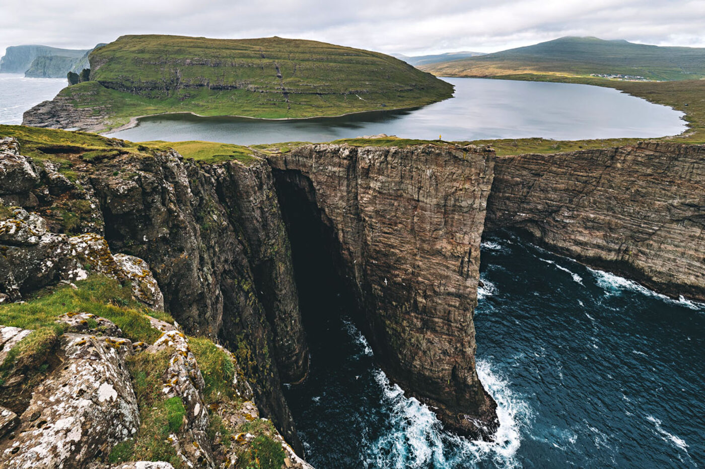 A photo of the cliffs above the water. The positioning of the photo makes it look like the water in the background of the image is above the water in the foreground of the image.