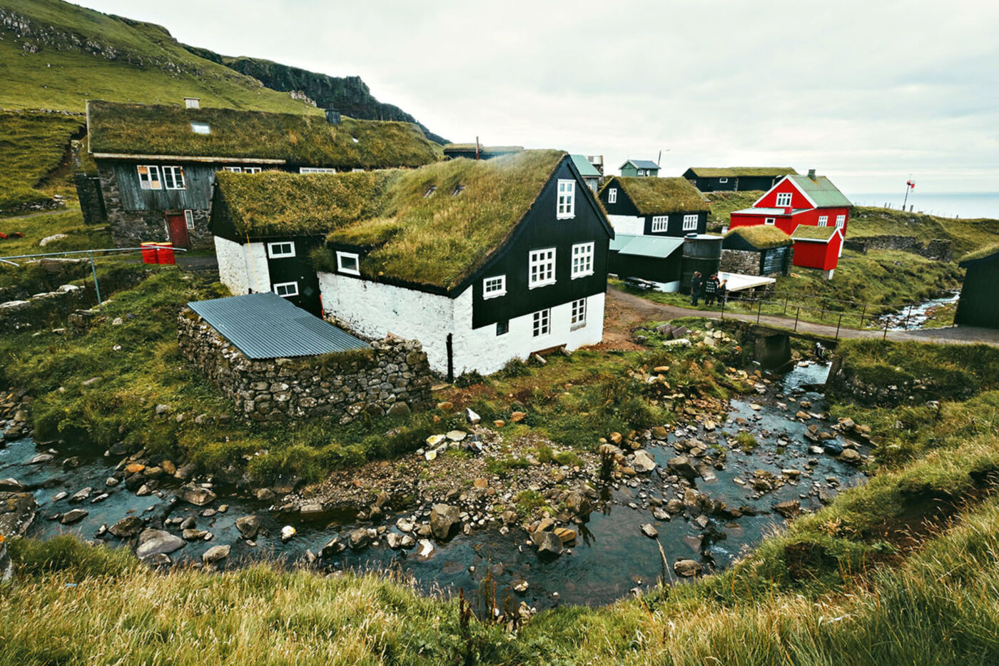 A group of houses with grass roofs near the water.