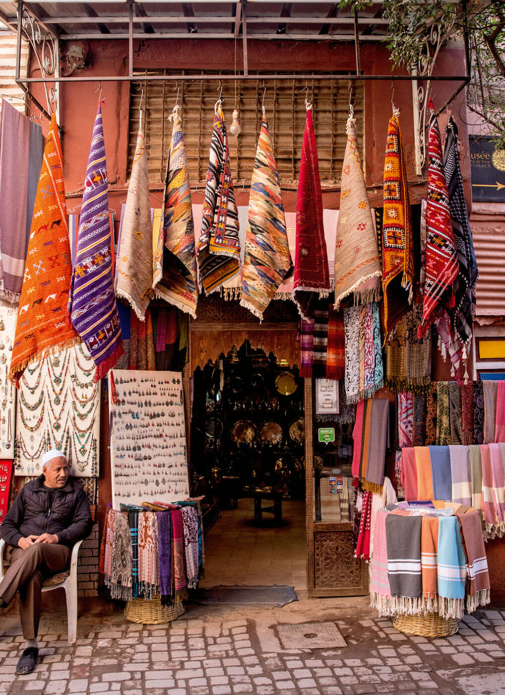 A person sitting outside a rug store.