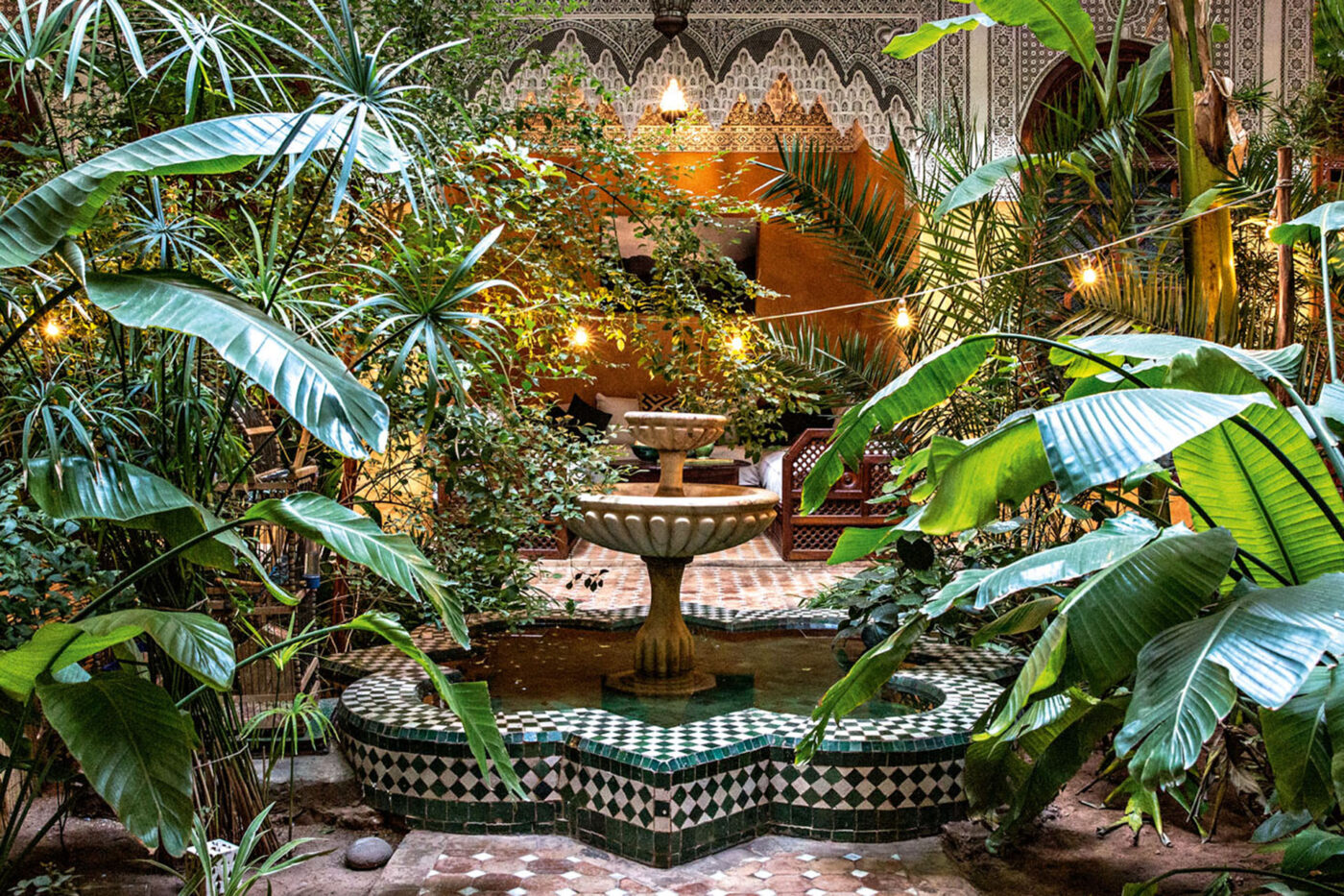 A big courtyard with a fountain in the middle, surrounded by greenery.