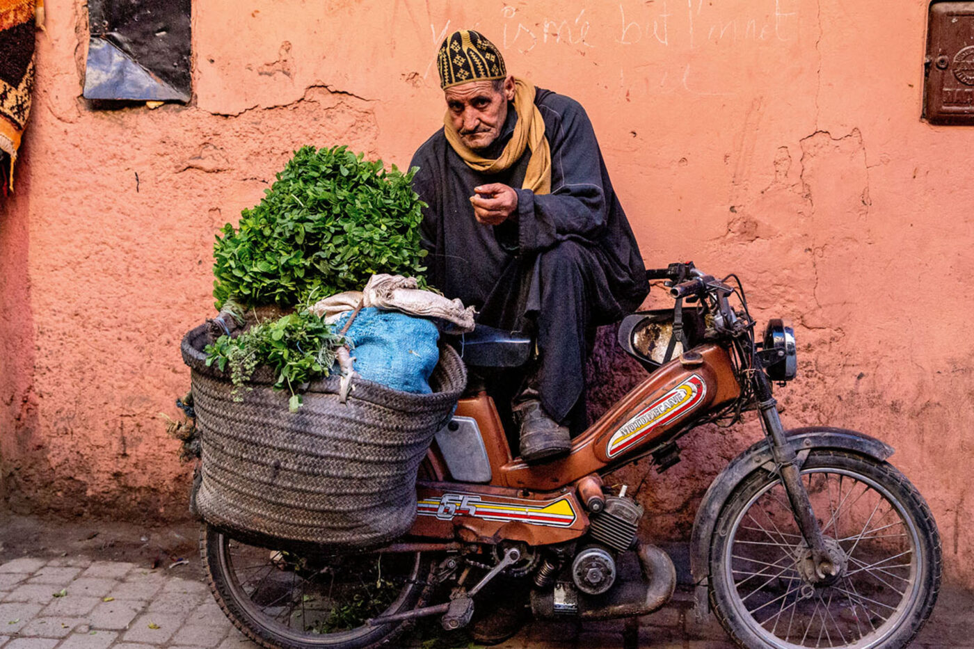 A local person sitting on a motorcycle with bags of groceries.