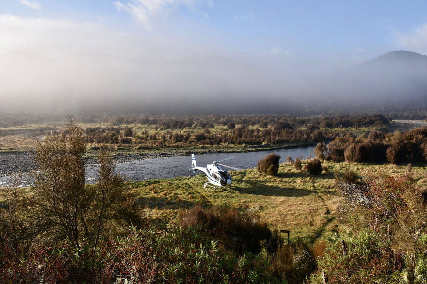A helicopter parked next to a lake.