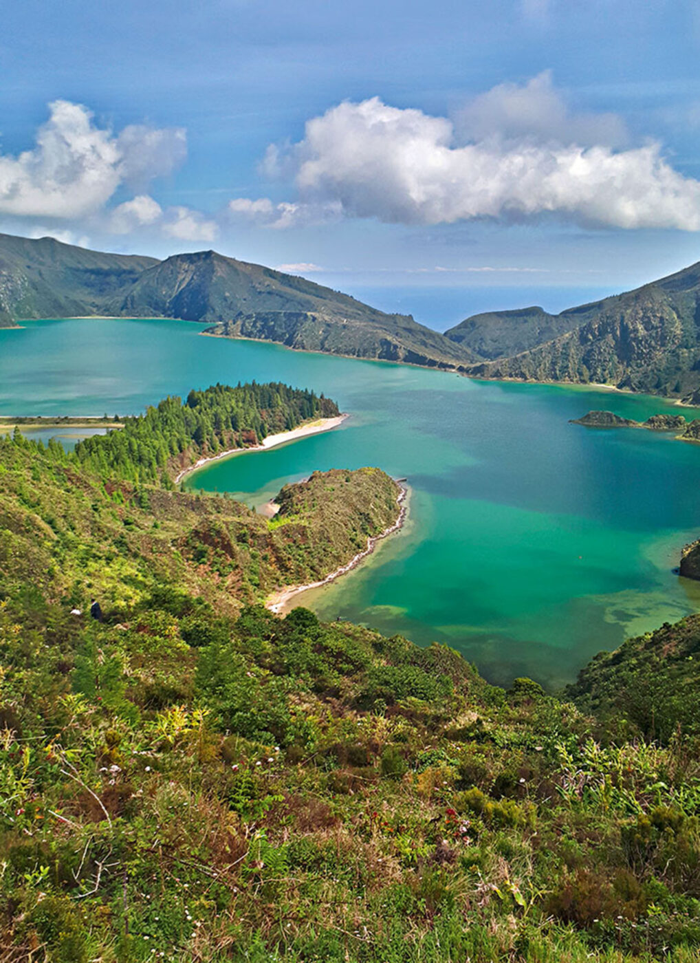 A landscape shot of a blue volcanic lake surrounded by greenery.