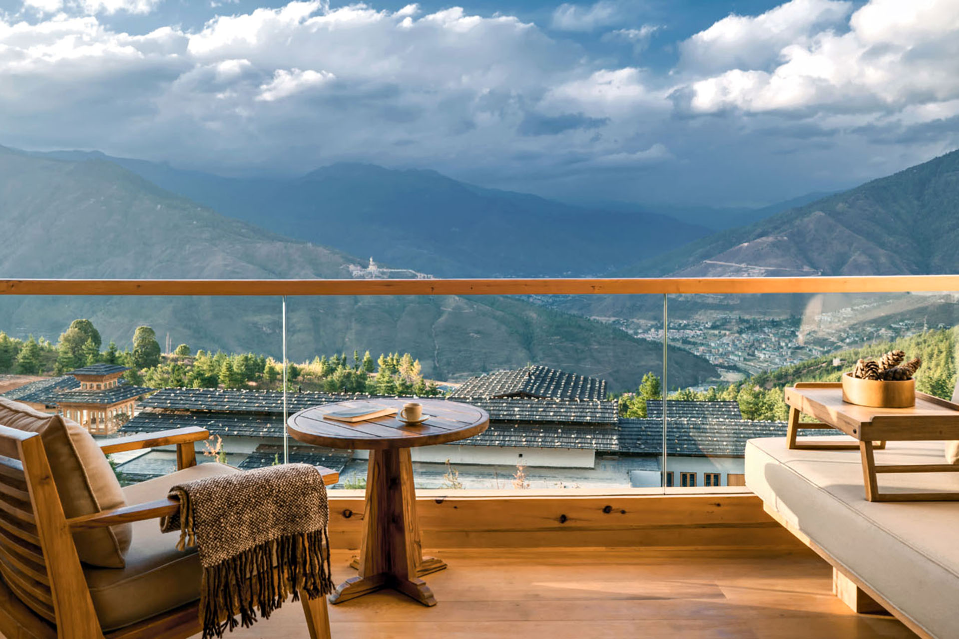 A balcony with cushioned chairs and a table looking over the mountains