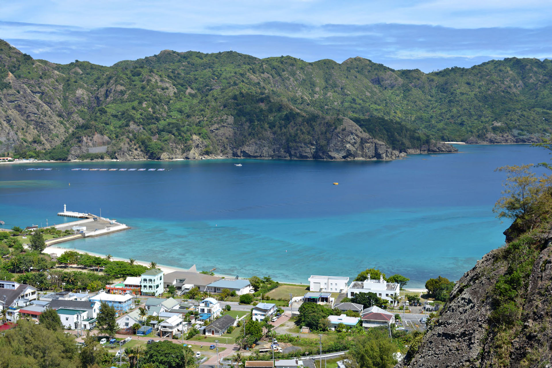 A group of houses by the sea. In the background, small mountains.