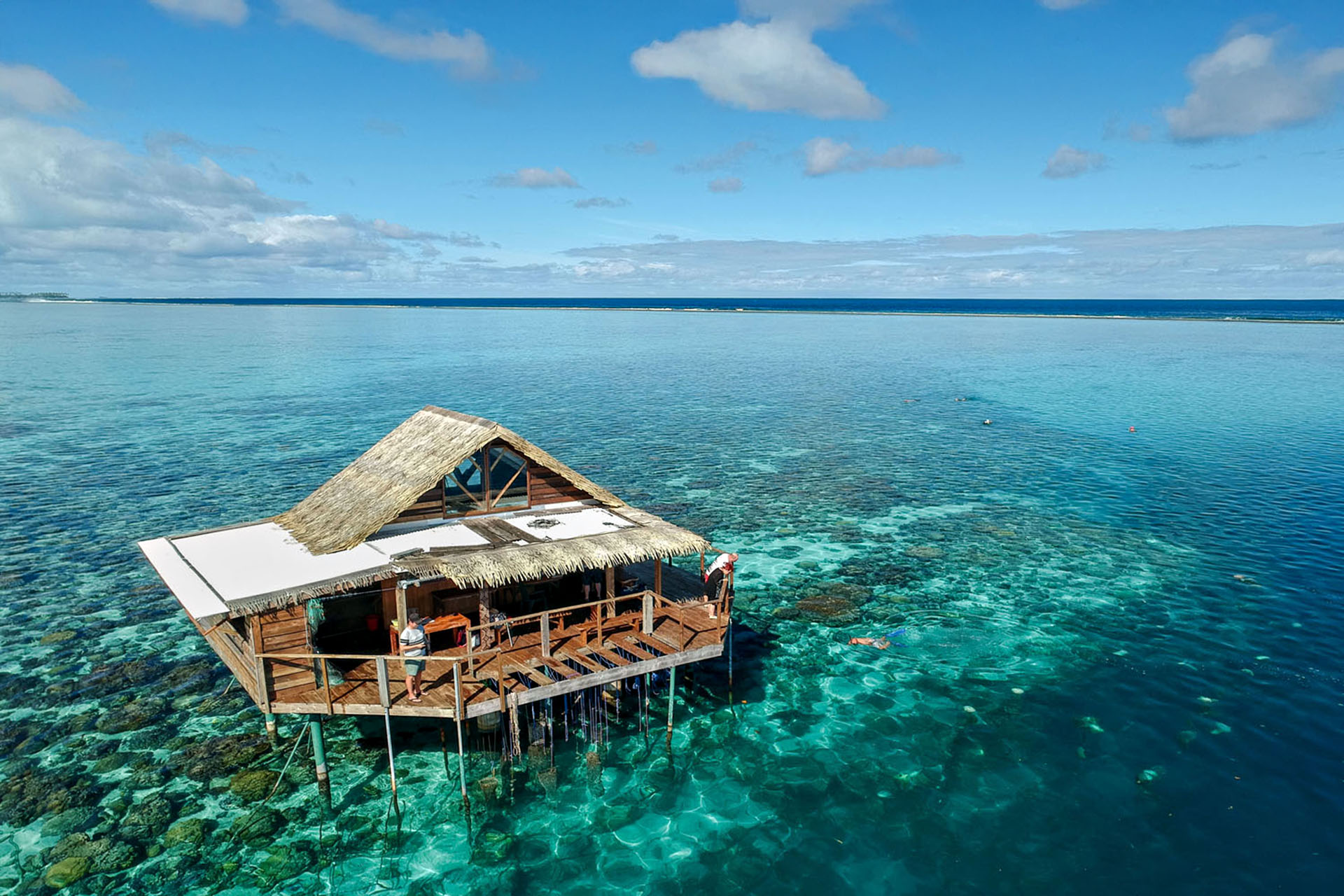 A shack in the middle of the shallow blue water.