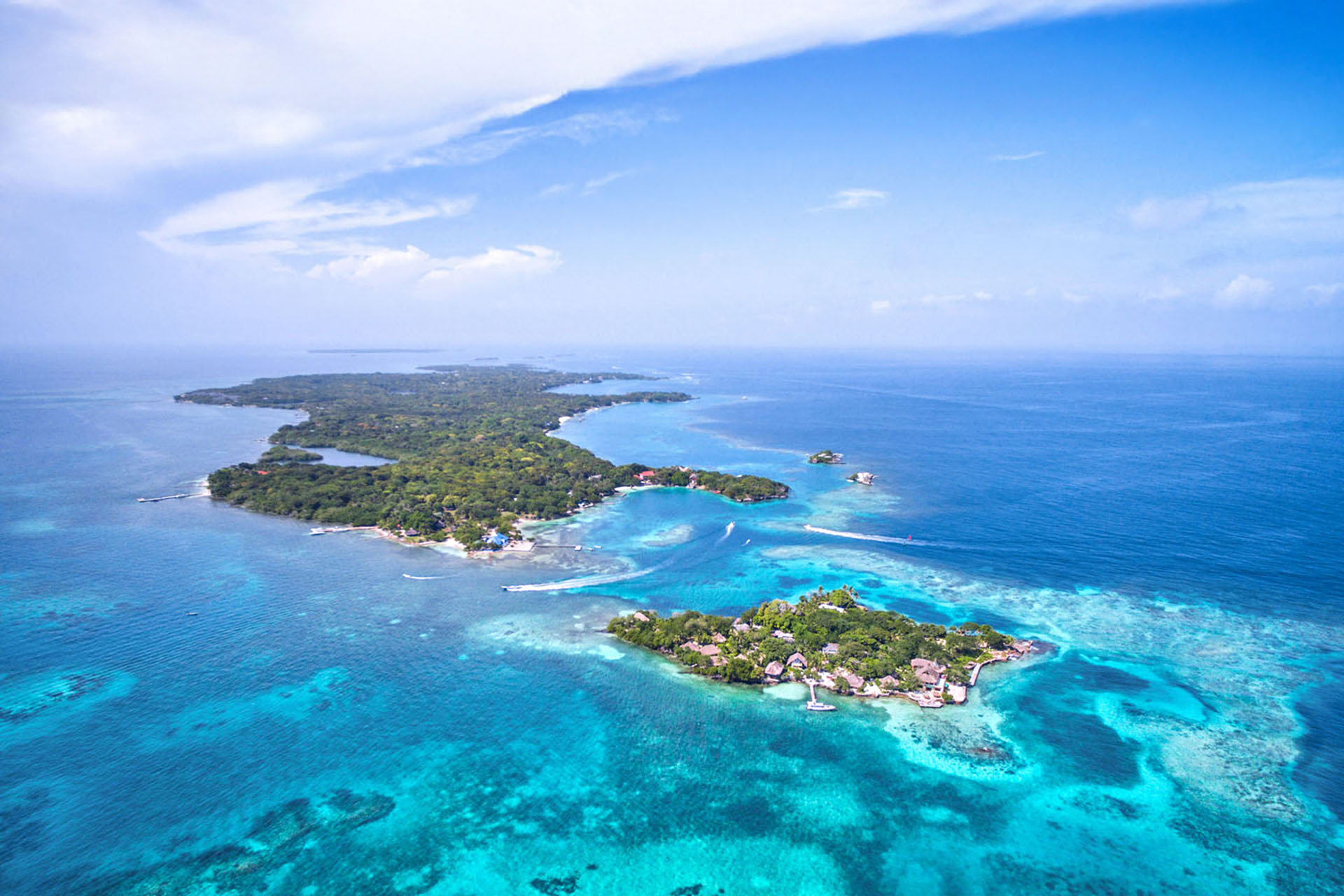 An aerial shot of the light blue water surrounding small islands with houses scattered across them.