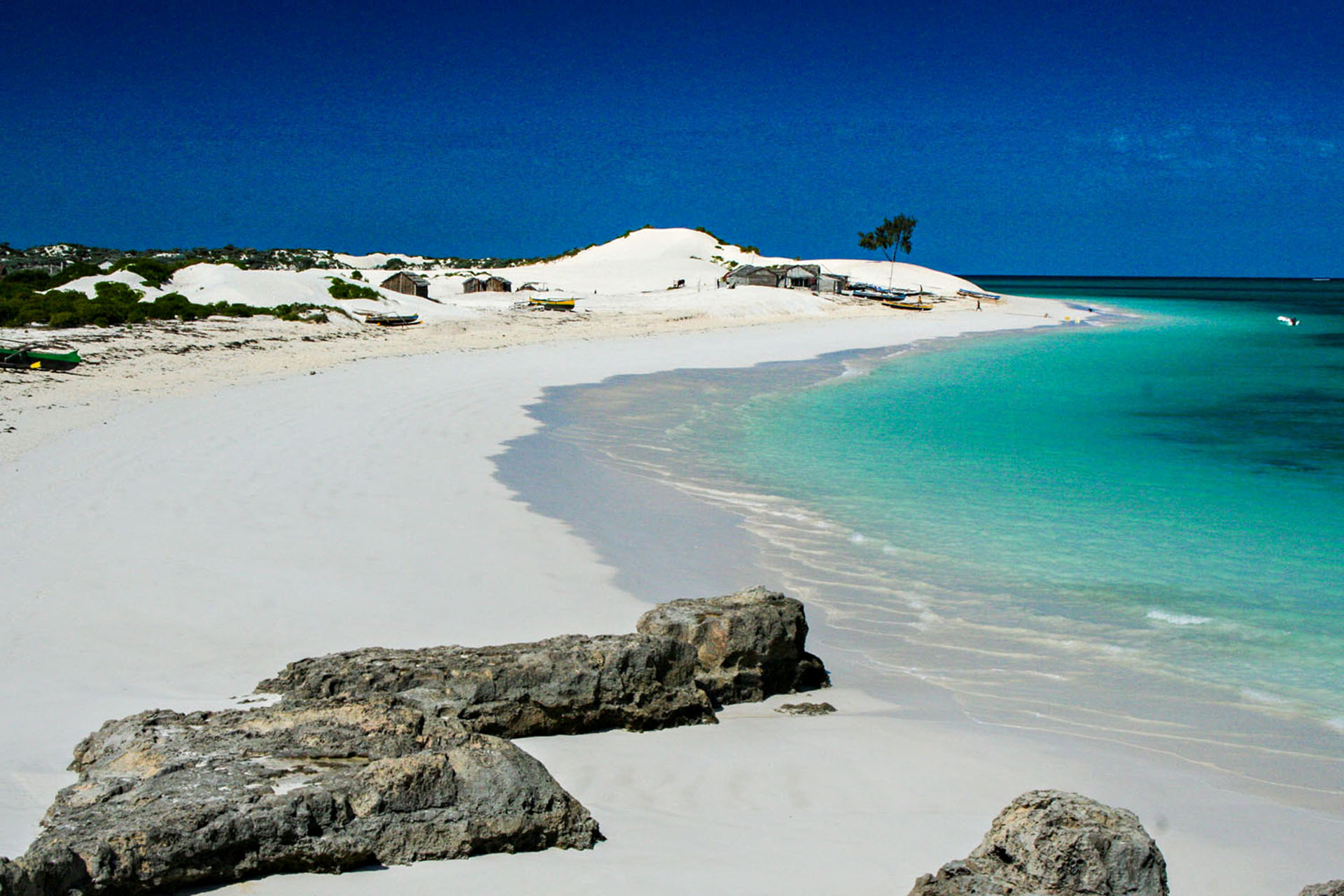 A windy beach with very white and, the water is a very light blue.