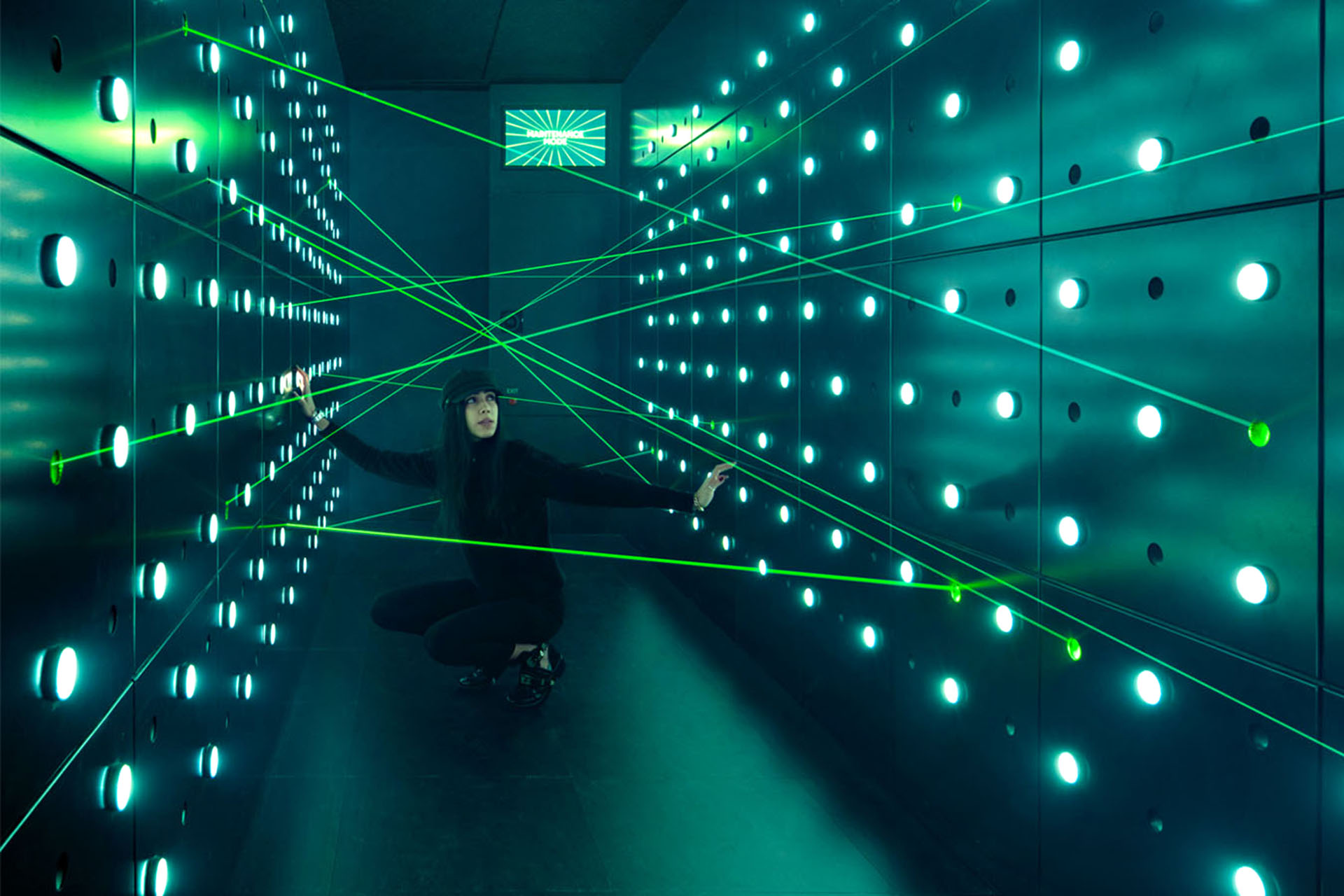 A person in a room filled with green lasers trying to avoid them.