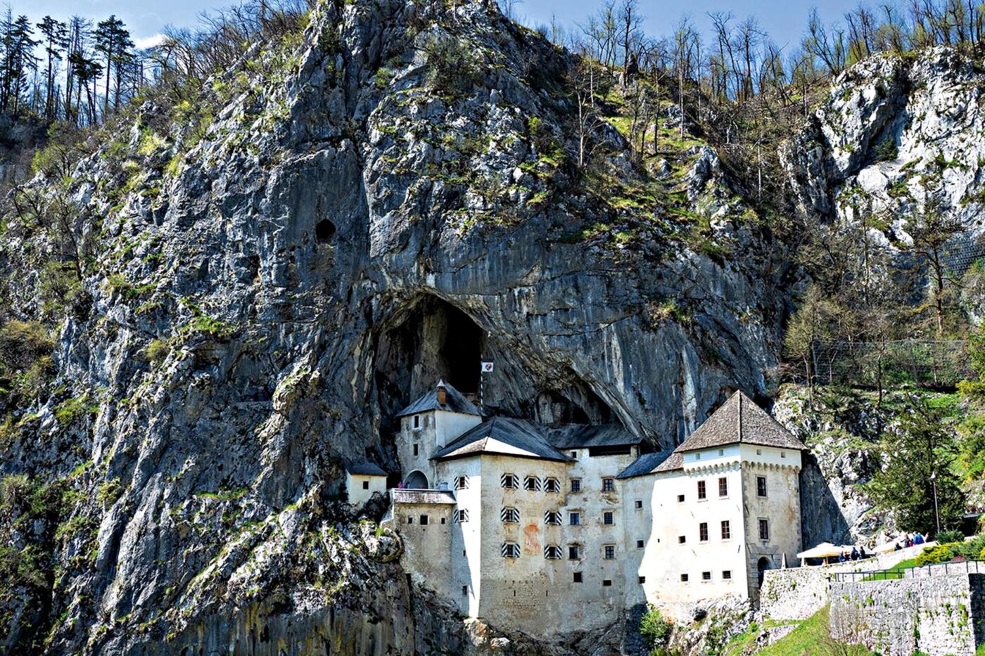 A white castle built into the side of a big cave.