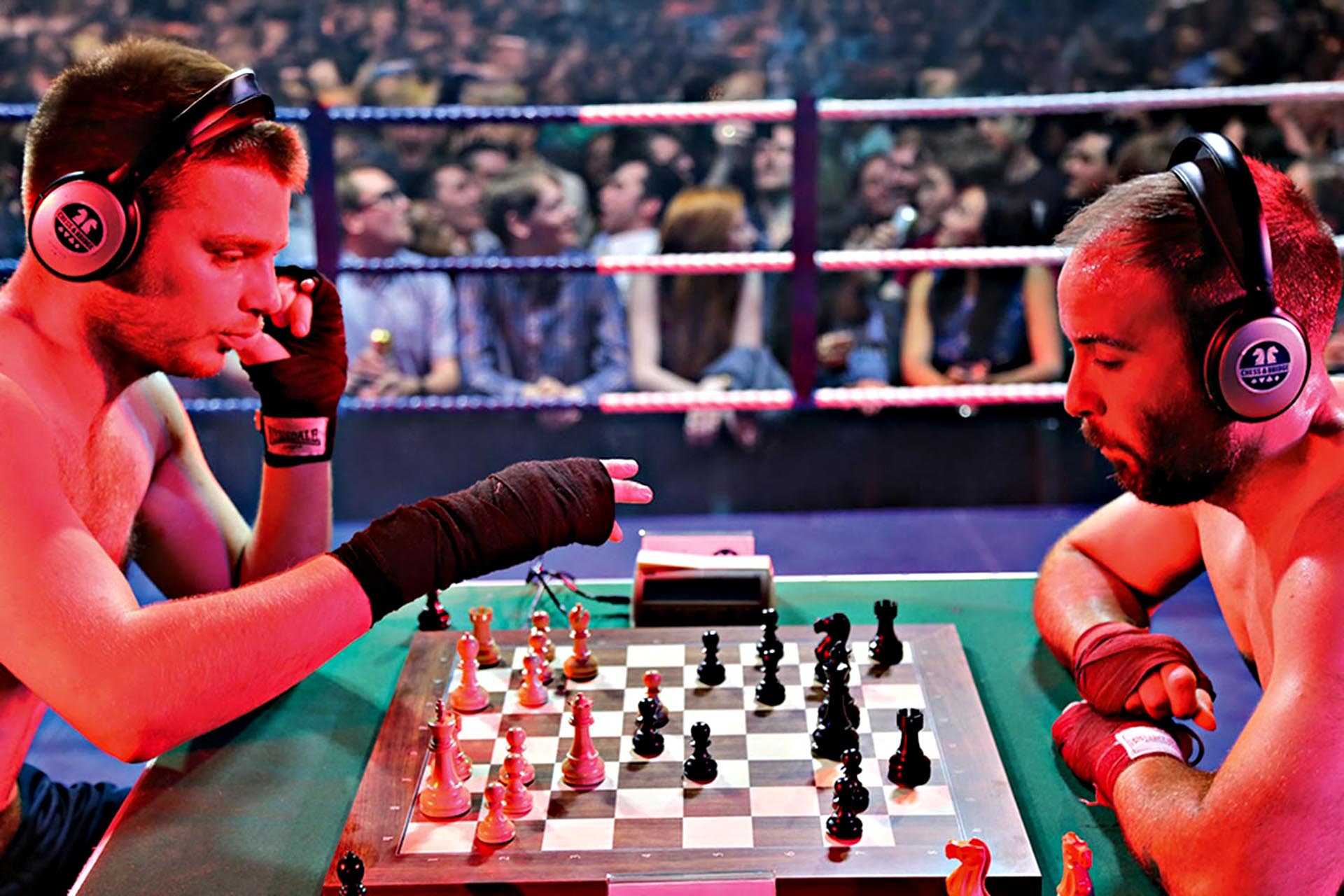 Two people in a heated chess competition in front of a large crowd of people.