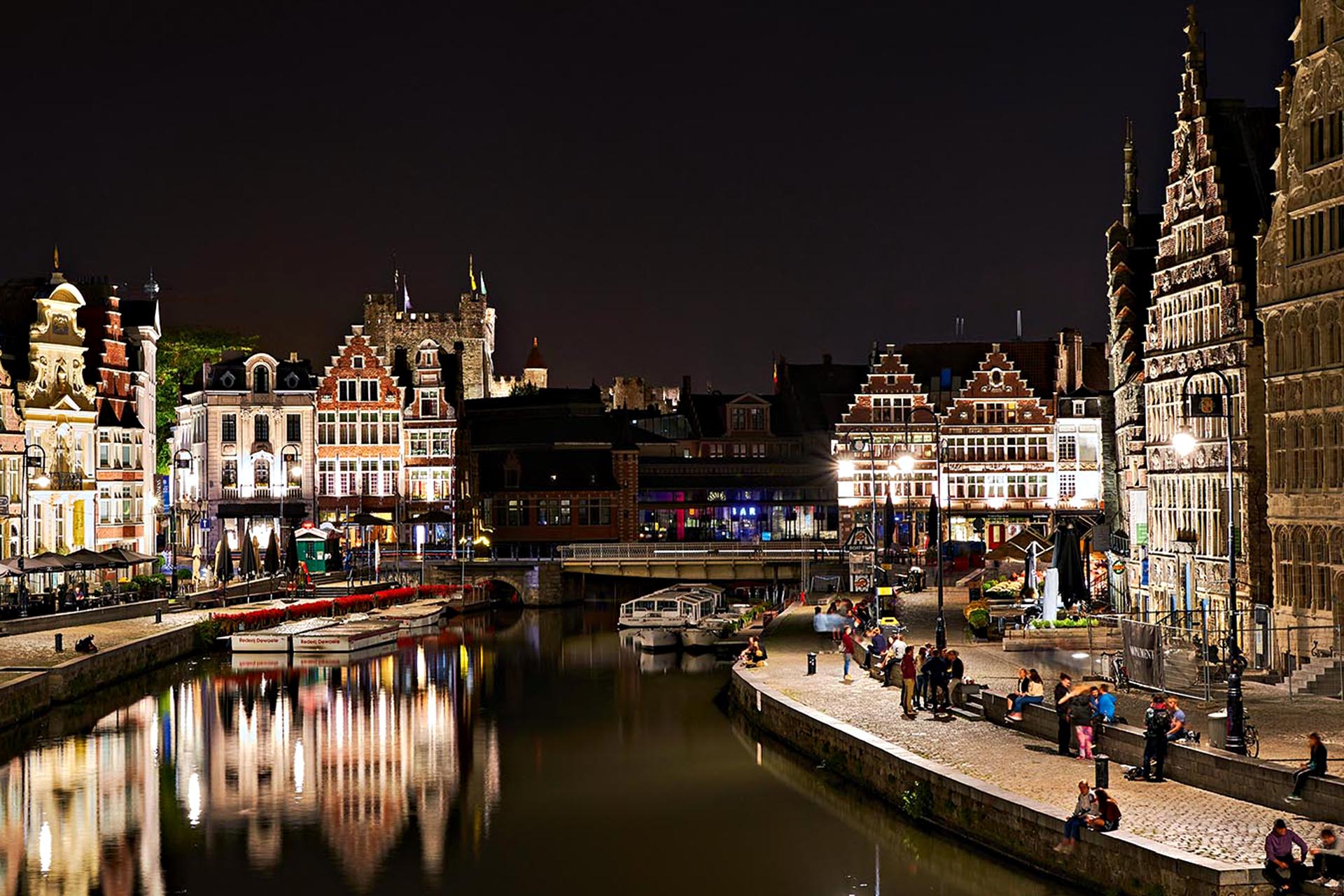 A city at night with grand architecture. A river runs through the middle of it.