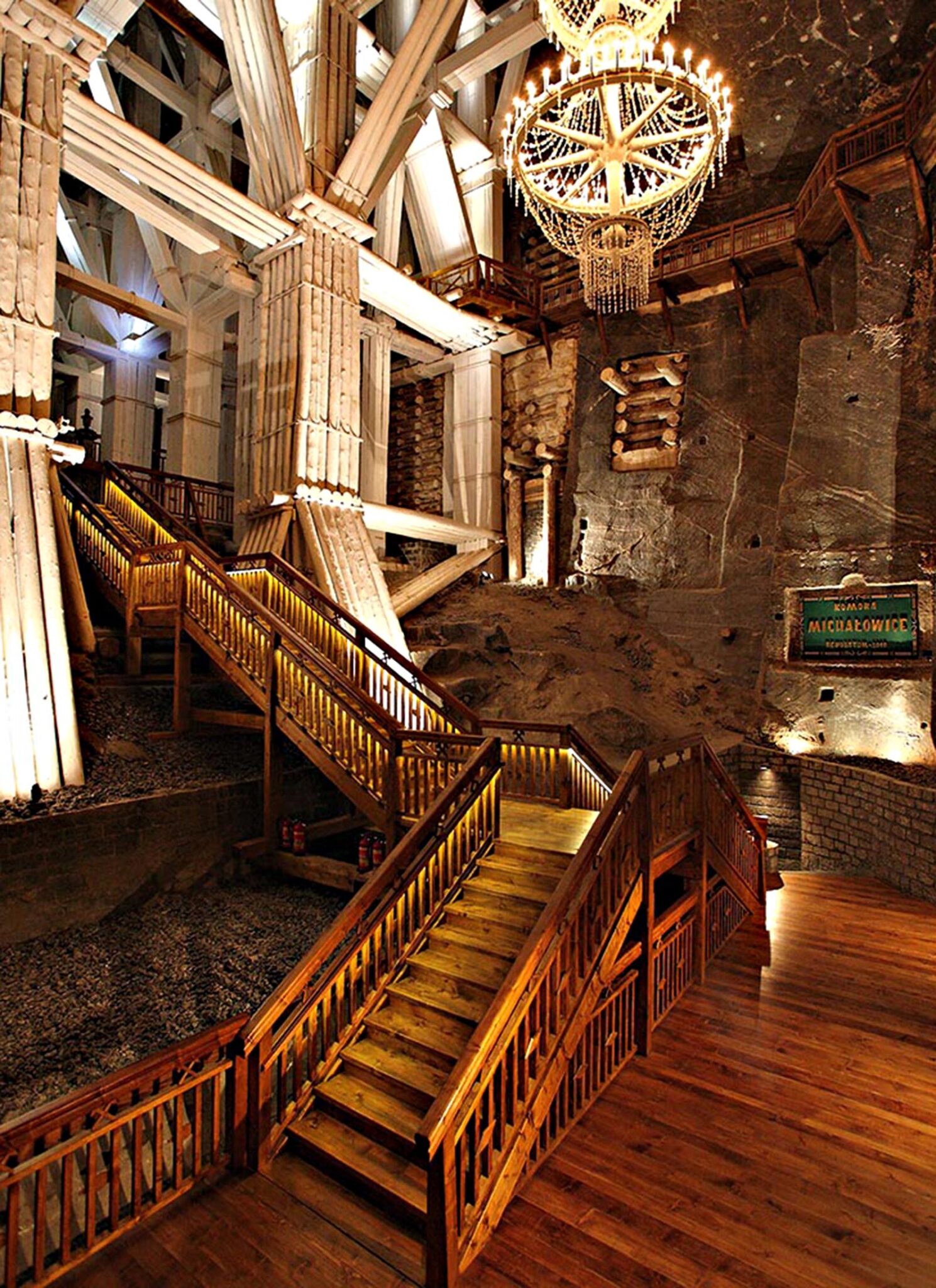 A grand room with a chandelier and wooden staircase.