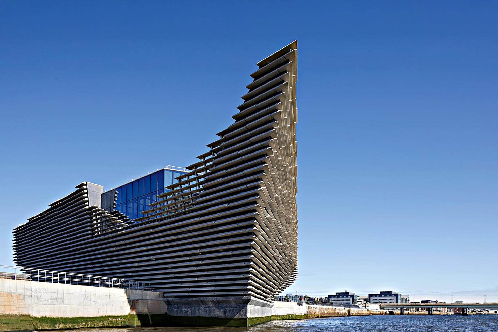 A building in the shape of a boat on the side of the water.