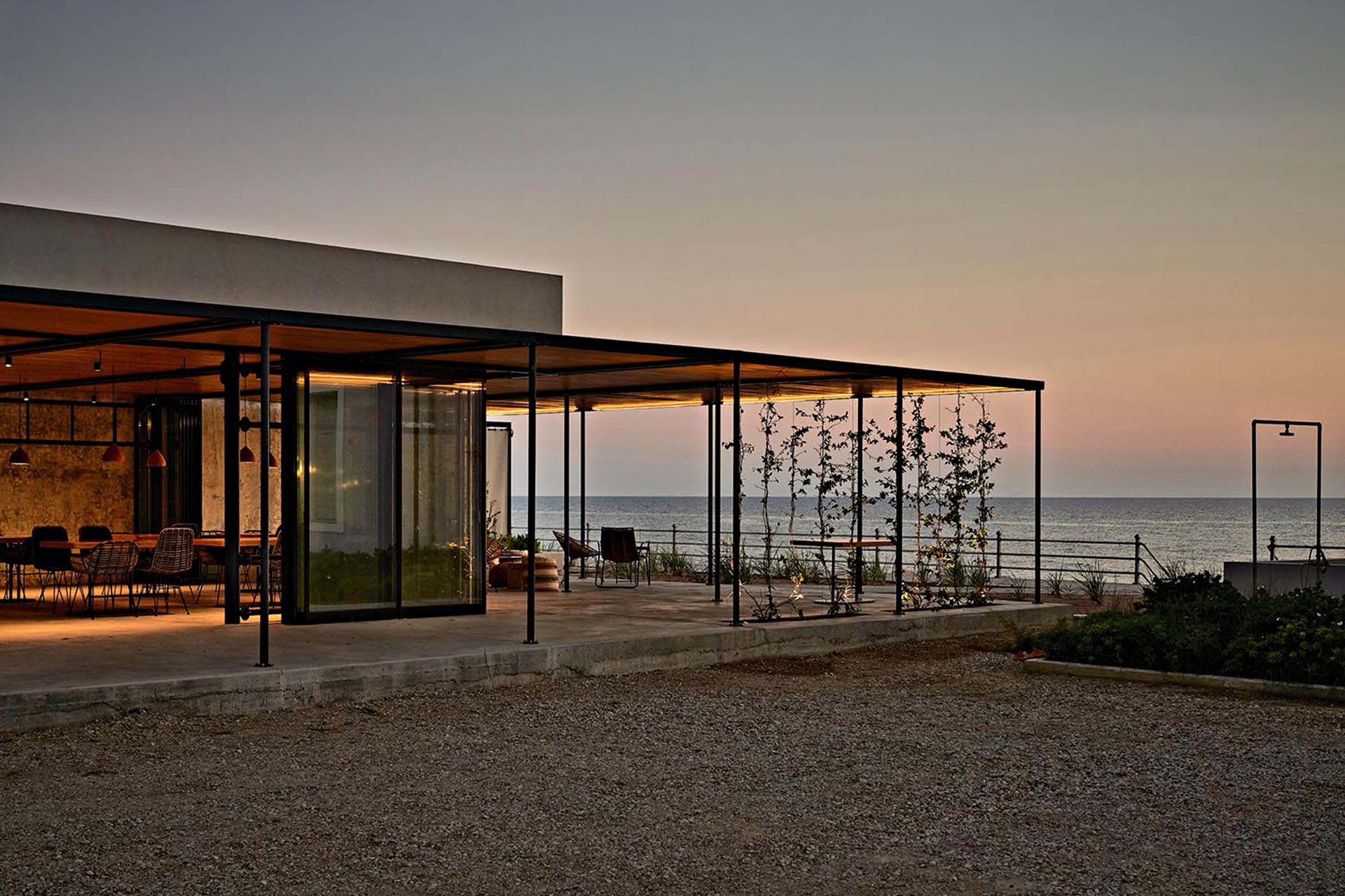 A modern, square house that looks over the ocean. With a patio that wraps around it.