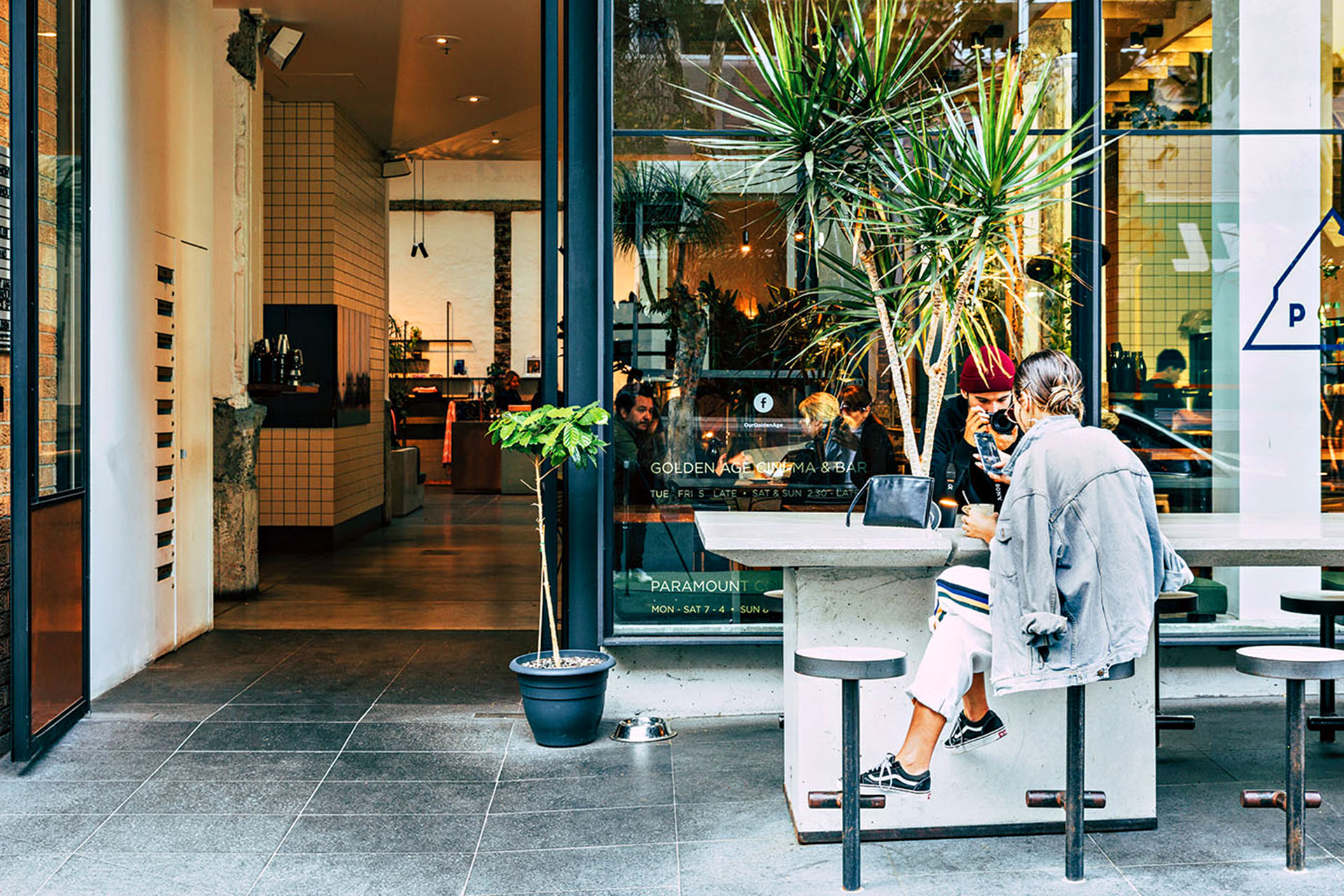Two people having coffee outside the front of a building.