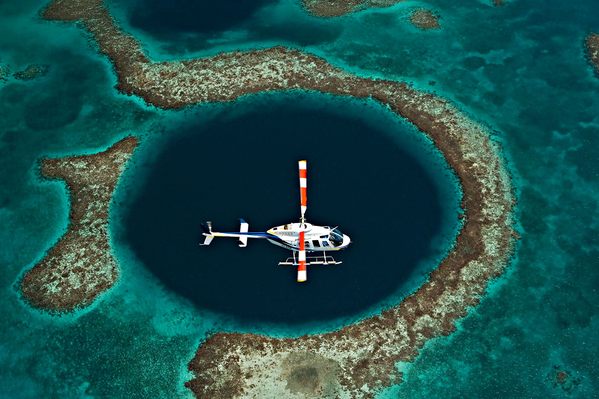 A helicopter flying over the great blue hole.