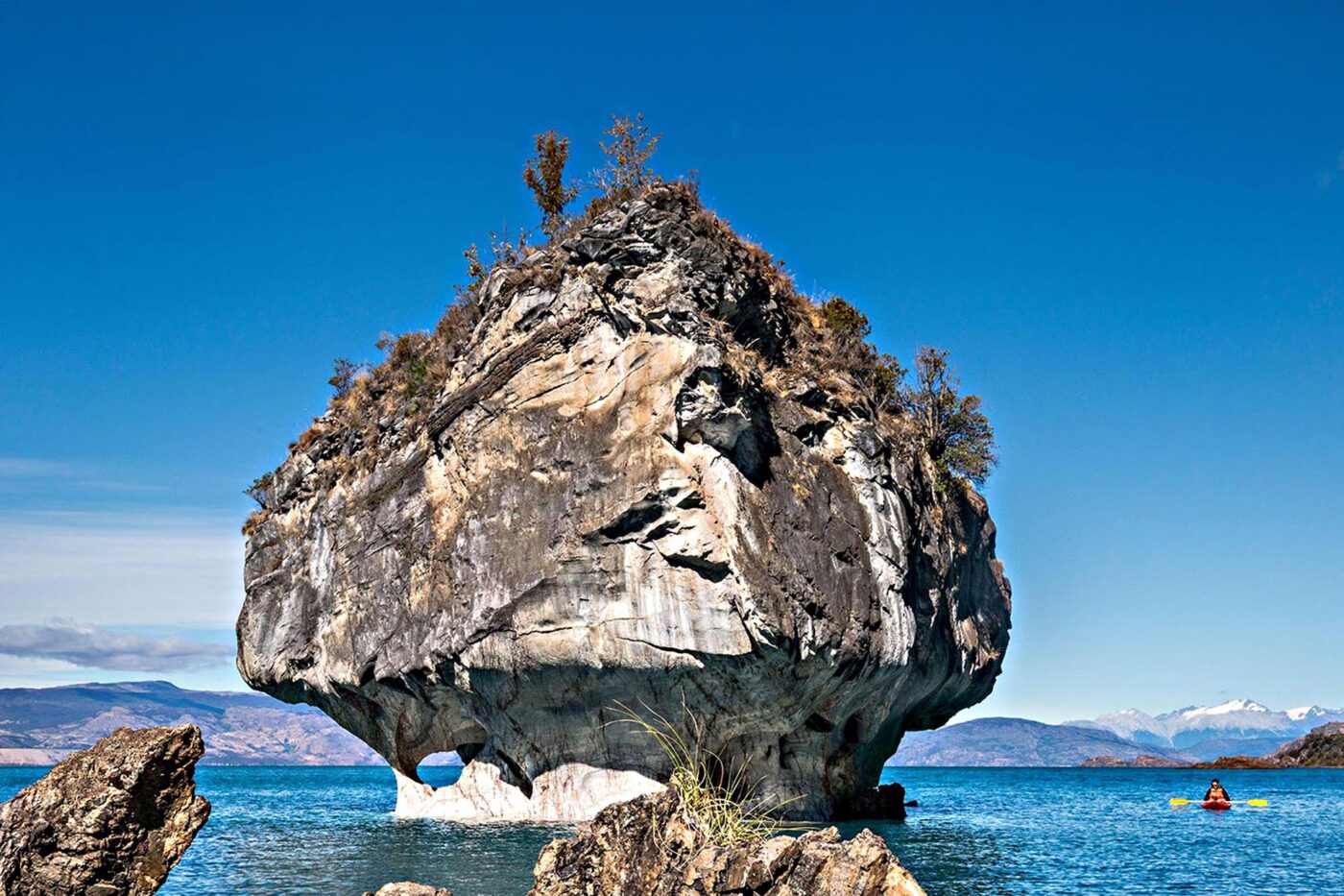 A big cave formation in the middle of the water.