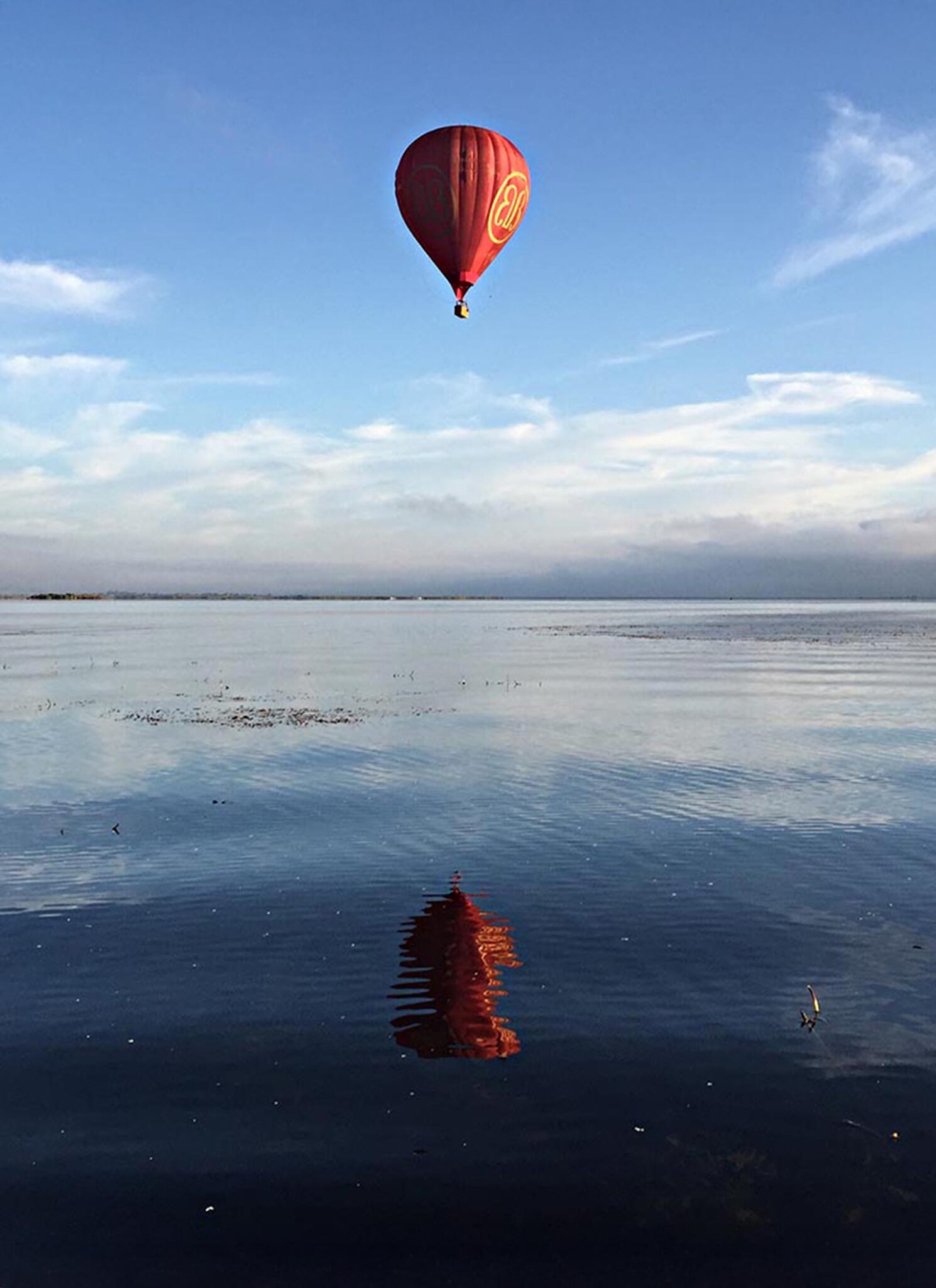 A hot air balloon floating over a lake.