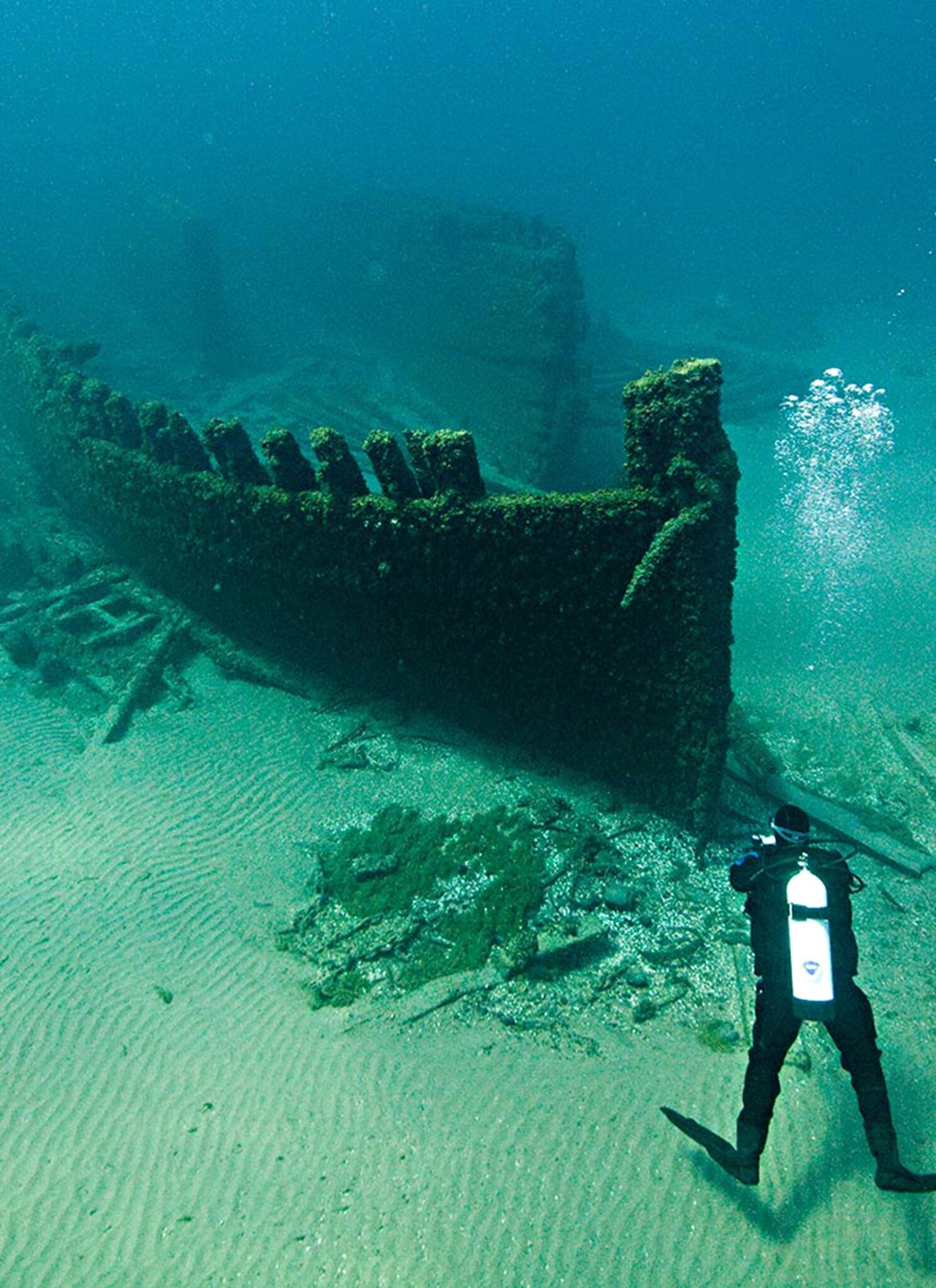 A diver taking a photo of a shipwreck underwater.