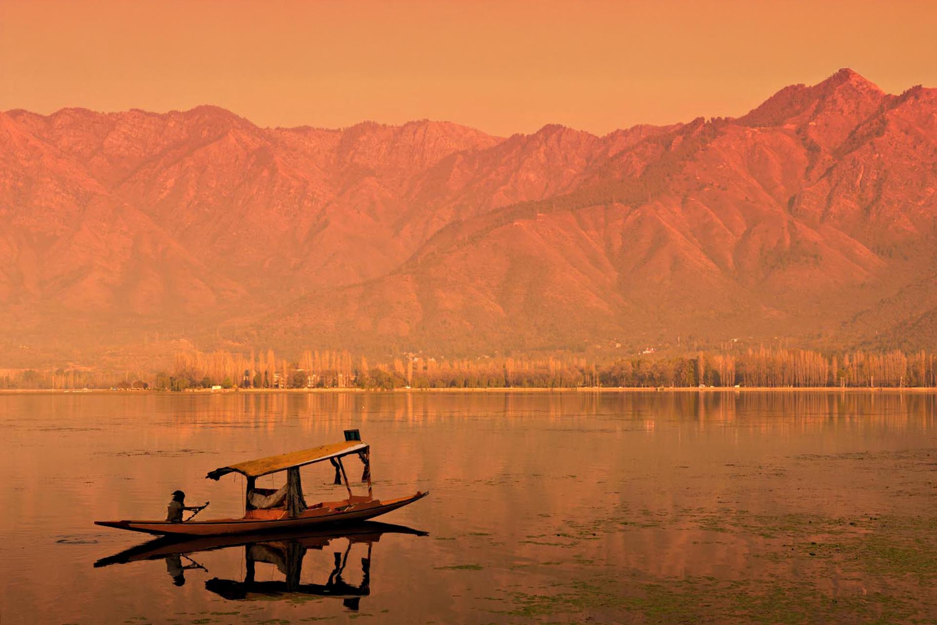 A houseboat floating over the water at sunset, an orange hue covers the landscape.