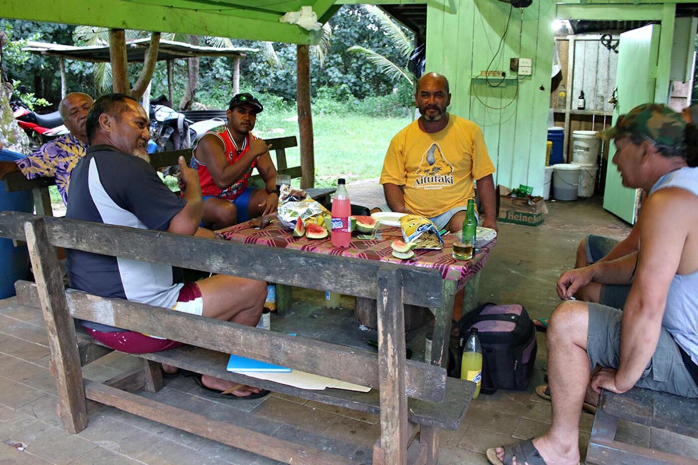 6 people chatting around a table full of snacks.