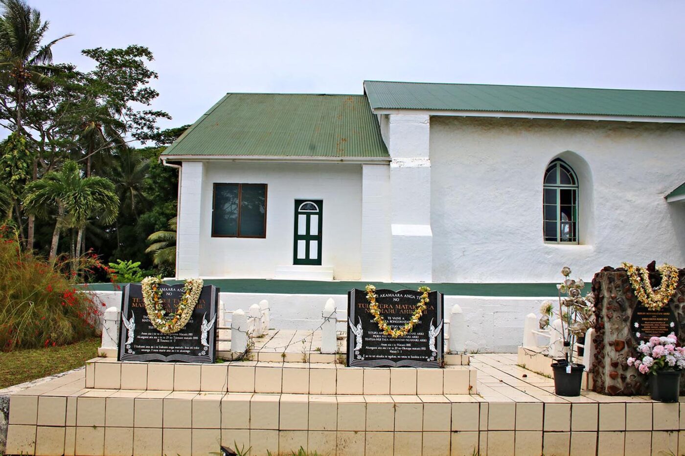 A green and white church, with 3 plaques in front of it.