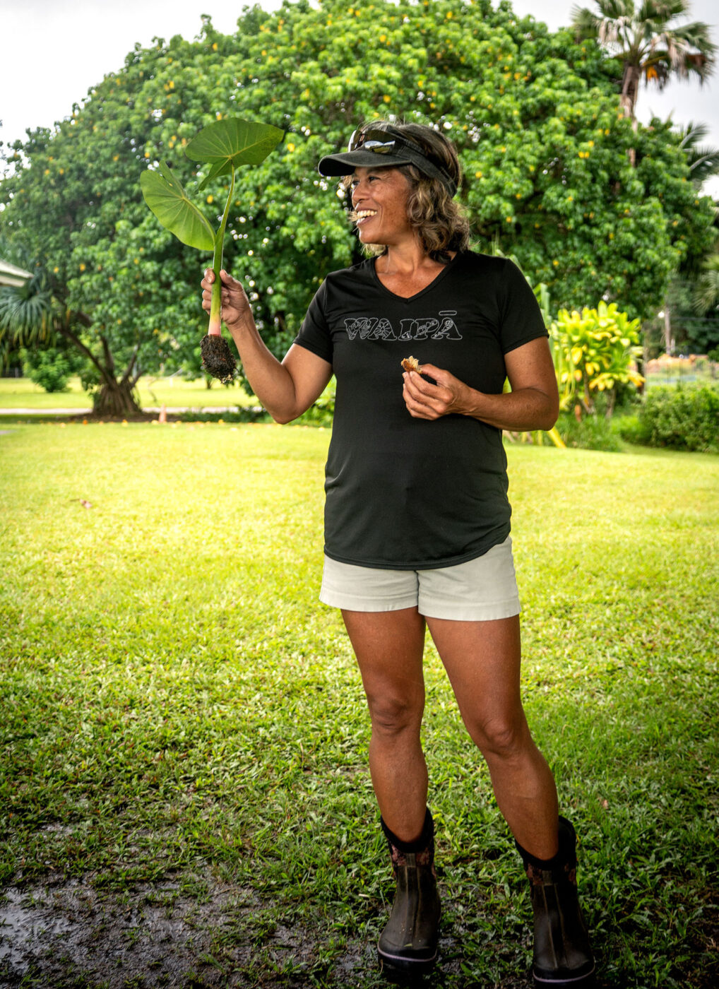 A woman smiling and holding up a plant.