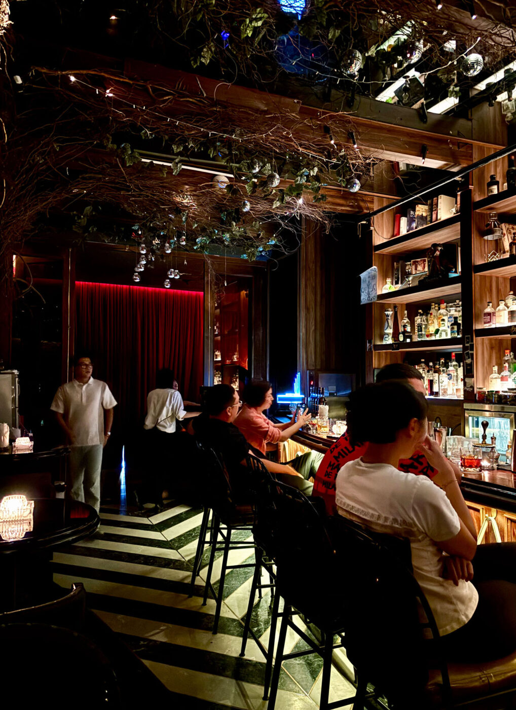 People sitting around a dimly lit, cocktail bar.