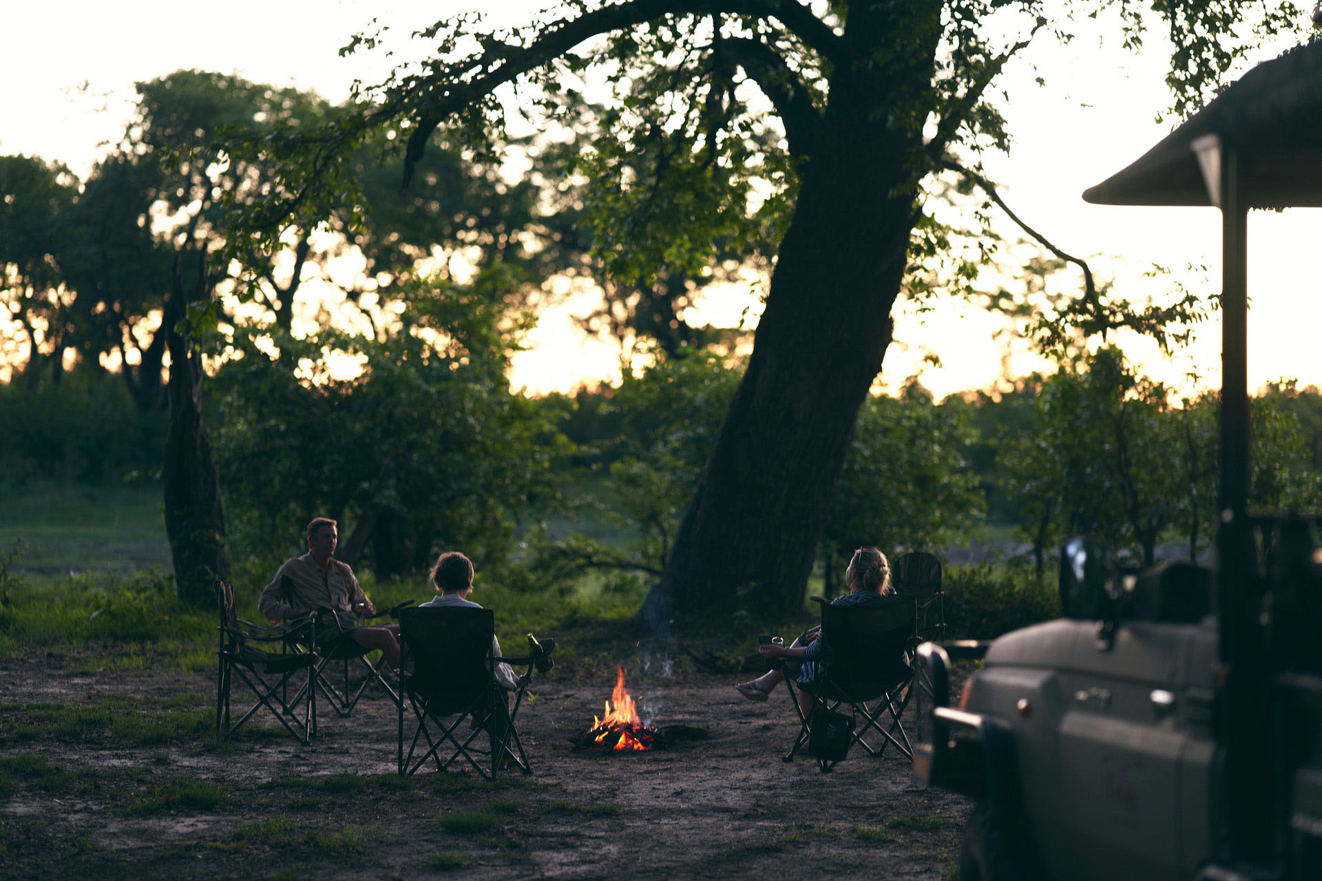 Travellers enjoying a sundowner around a campfire in Botswana.
