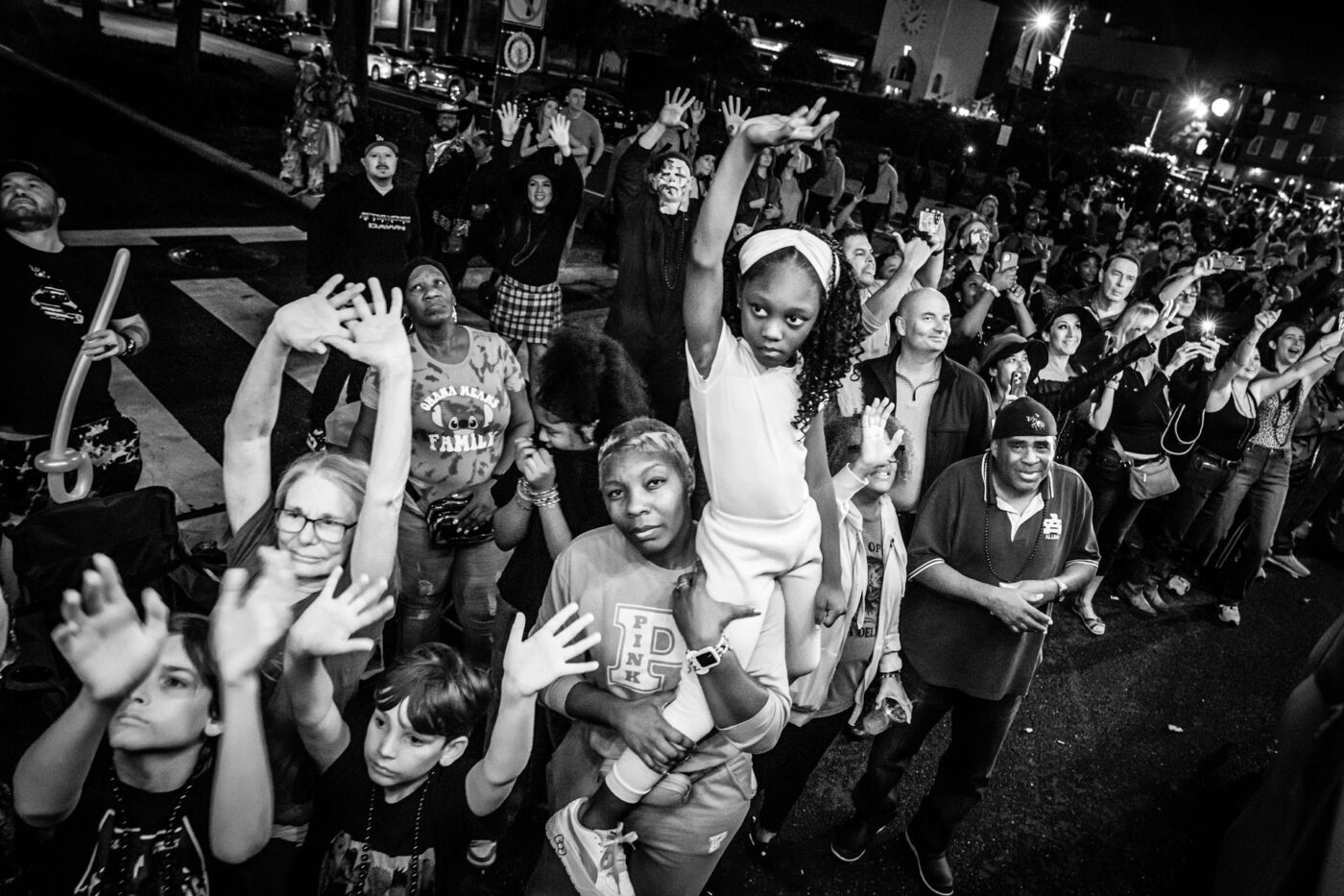 A black and white photo of a huge crowd all putting their hands up.